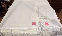 Stacks of white tie-top curtain panels, one opened to show ties and size