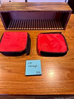 Wooden CD rack and two red CD wallets on tabletop