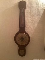 Full view of wall-mounted wooden weather station showing thermometer, barometer, hygrometer