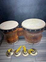Front view of joined wooden bongos and four brass castanets