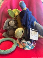 Group of dog toys including plush donkey, turtle, banana, green rubber ring and sun hat