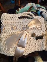 Chunky off-white crocheted handbag with ribbon and pin