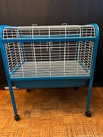 Front view of blue frame small animal cage with white wire panels and plastic tray