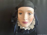 Front view of mime mask showing facial features, lace and satin ruffle collar, ribbon ties