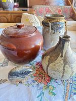 Group shot of all four items: lidded pot, vase with rope, jug, stone animal