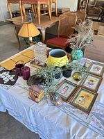 Overview of all items on table including lamp, trays, stained glass, faux plants, framed prints and assorted décor