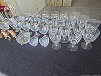 Rows of clear goblets, pressed glass bowls and ceramic figurines on table
