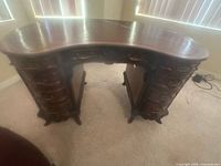 Front view of kidney-shaped desk showing drawer arrangement and pedestal bases