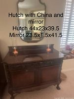 Carved wooden hutch with wood-framed mirror above