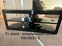 Front view of black TV stand showing glass shelves and open design