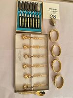 Full lot view: boxed spoons, boxed forks, napkin rings, shell dish