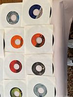 Multiple 7" records in white sleeves arranged on surface