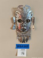 Front view of silver metal tribal mask with dangling ornaments
