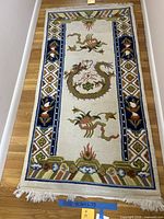 Full view of rectangular wool rug showing dragon design, border, fringe