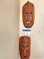 Two wooden masks on wall, full view of both
