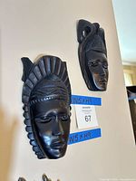 Two black wood wall masks hanging on wall