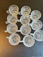 Top view of 12 pressed glass cups showing pattern and handles