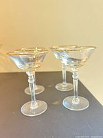 Four gold-rimmed martini glasses angled view