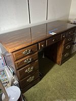 Front and top view of dark brown wood veneer desk showing five drawers and brass-tone hardware