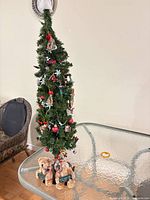 Full view of decorated tabletop Christmas tree with plush bears at base