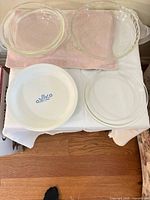 Five pie plates displayed: four clear glass, one white ceramic with blue cornflower