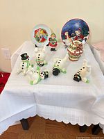 Overall lot showing snowman figurines, plates, child figurine and votive holder