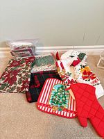 Overview of all Christmas linens including oven mitt, pot holder, towels, placemat, bag of napkins