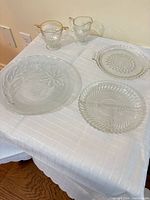 All five glass items on table: sugar bowl, creamer, three serving plates