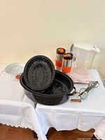 Group shot of roaster, lids, mugs, pitcher, casserole, egg beater