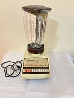 Front view of Osterizer Classic Pulse Blend 10 blender showing 10 push-buttons, glass jar, lid and power cord