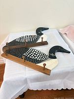 Both wood coat racks showing loon design and peg hooks