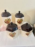 All four ceramic canisters showing size difference and fruit motif