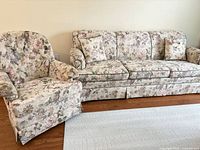 Sofa and matching armchair side by side on wooden floor with rug foreground