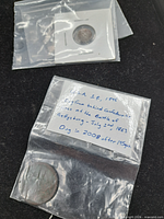 coin flip containing metallic fragment and separate bag with corroded coin and handwritten note