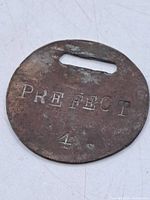 Front of badge showing PREFECT 4 stamping and patina