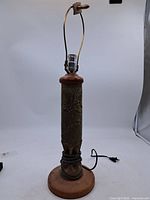 Full view of brass shell casing lamp with wood base, harp and cord