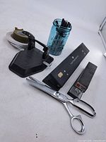 Overview of all items: two-hole punch, three-hole punch, stapler, scissors, glass jar with markers, tape roll
