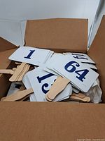 Open box showing many bidding paddles with numbers visible (1,64,13)
