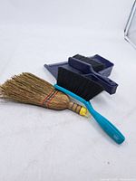 All items laid out: dustpan, two brushes, straw whisk broom