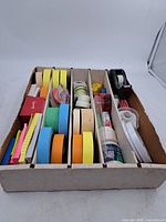 Overall view of cardboard organizer with assorted tapes, dispensers and sticky notes