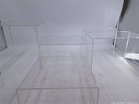 Three Lucite riser stands on white backdrop showing varying heights