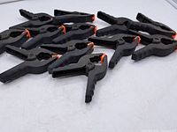 Group of ten identical black plastic spring clamps arranged on table