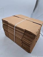Stack of flat brown corrugated mailer boxes bound with white strap