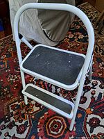 Front view of white folding step stool with two black tread steps
