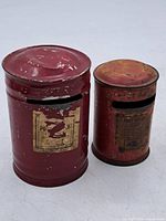Front view of both tin banks showing sizes, slots, labels, paint wear