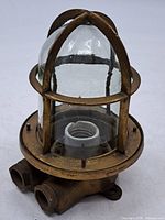 Overall view of brass ship corridor light with cage and glass globe