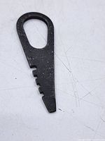 Full view front of flat steel tool showing loop handle, notched edge and tapered tip