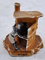 Front view showing outhouse, figure, base inscription