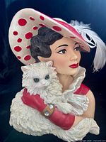 Front view of ceramic head vase showing woman's face, hat, gloves and cat