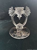 Frontal view of candlestick showing winged arms, teardrop element, and silver overlay design on base